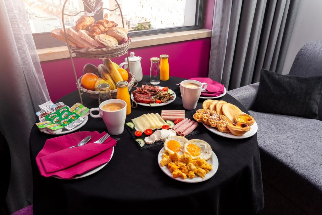 An abundant breakfast is arranged on a small round table beside a window.
