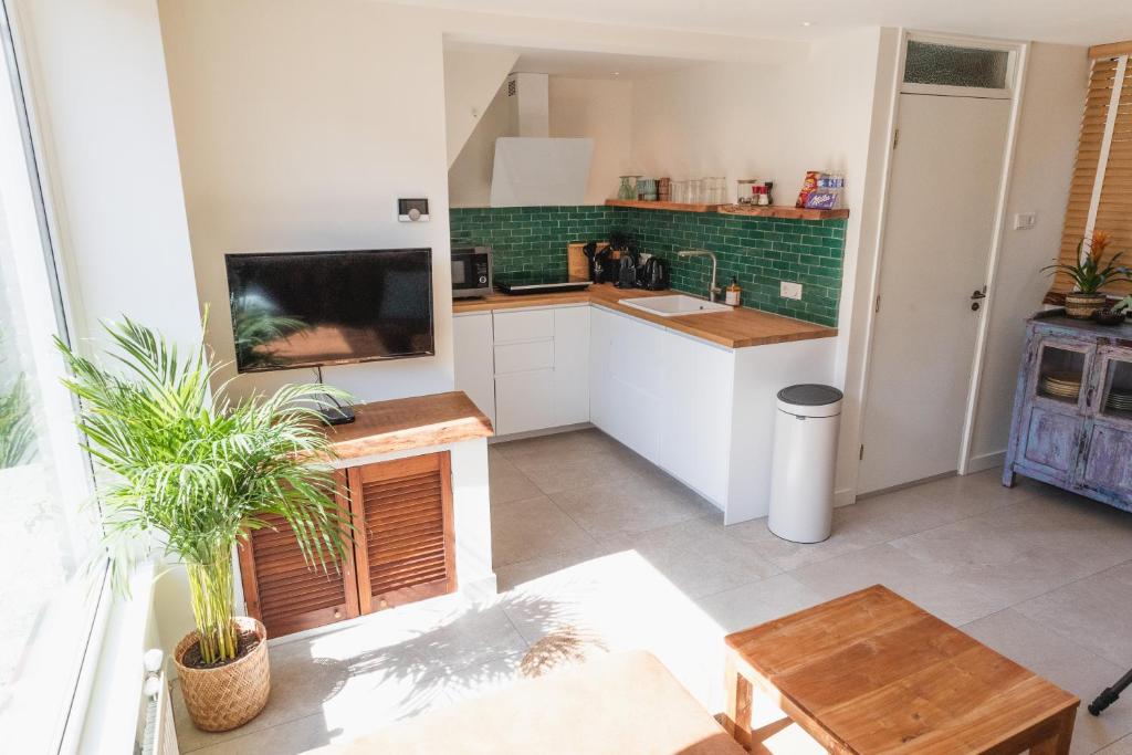 a kitchen with white cabinets and a tv and a table at Kelp in Egmond aan Zee