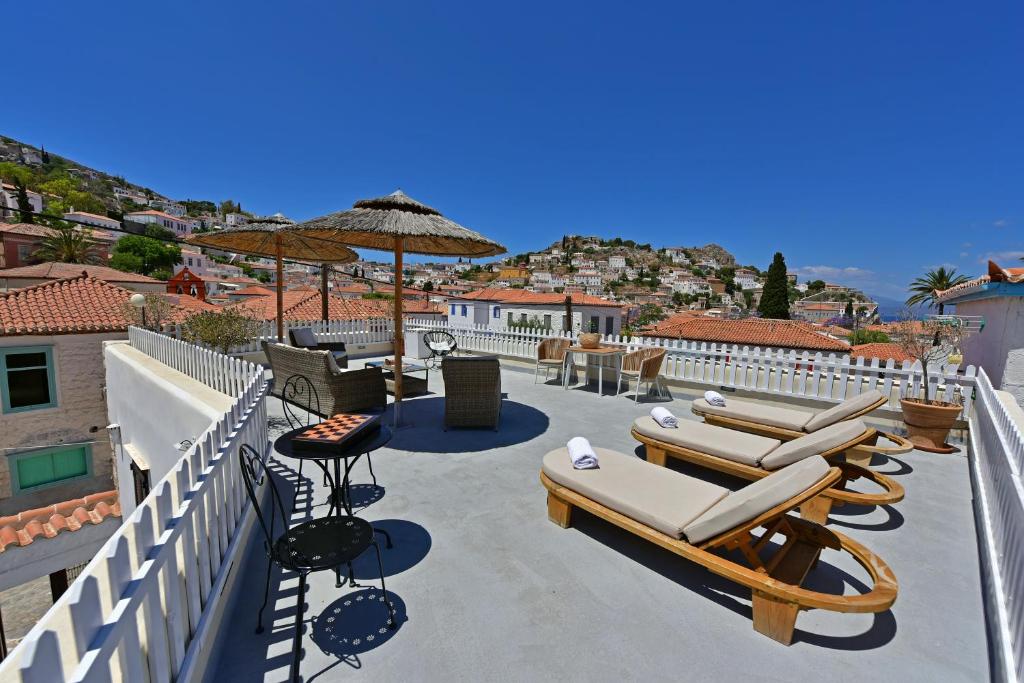 a patio with lounge chairs and umbrellas on a roof at Unique luxury suites in Hydra