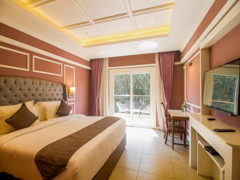 De Amour - A Dreamy Getaway in Anjuna في أنجونا: غرفة نوم بها سرير ومكتب وتلفزيون