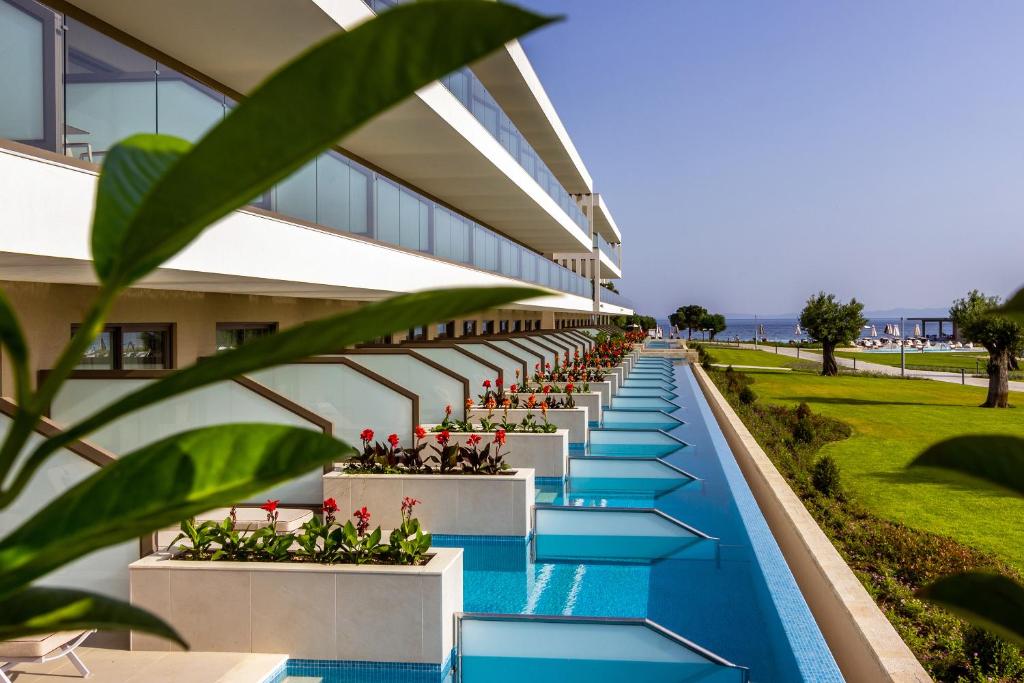 an external view of a building with a pool and plants at Ammoa Luxury Hotel & Spa Resort in Nikiti