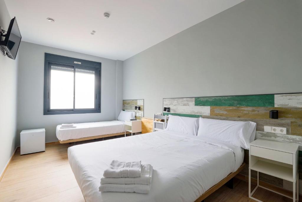 1 dormitorio con 1 cama blanca grande y toallas. en Hey Rooms, en Cerdanyola del Vallès