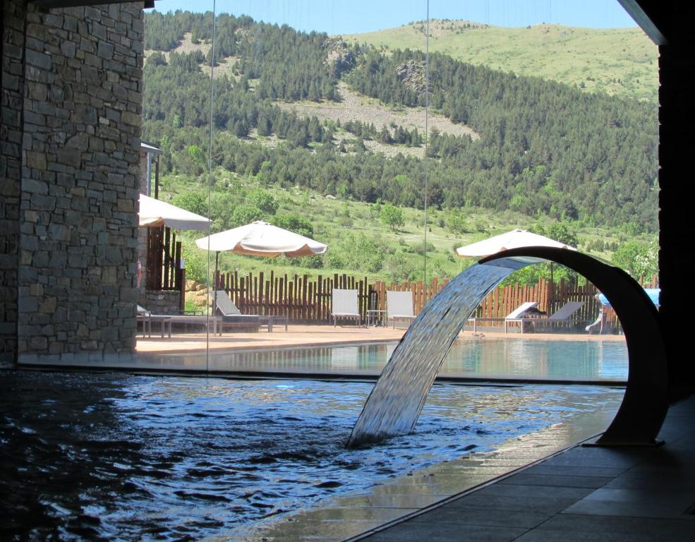 una fontana in una piscina con montagna di Aparthotel Siente Boí & SPA a Pla de l'Ermita