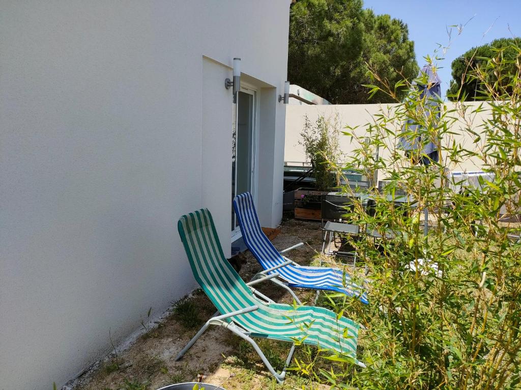 2 chaises assises dans une cour à côté d'un bâtiment dans l'établissement La Casita Sérignanaise - Apt T2 - clim - jardin, à Sérignan