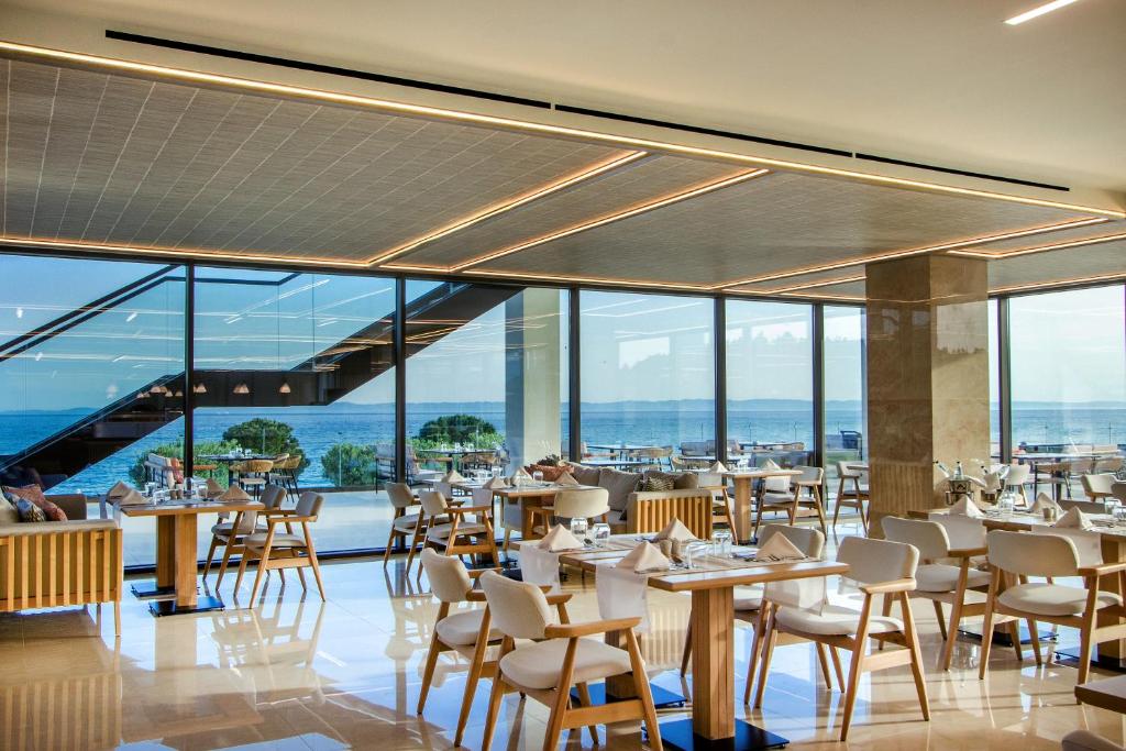 a restaurant with tables and chairs and windows at Ammoa Luxury Hotel & Spa Resort in Nikiti
