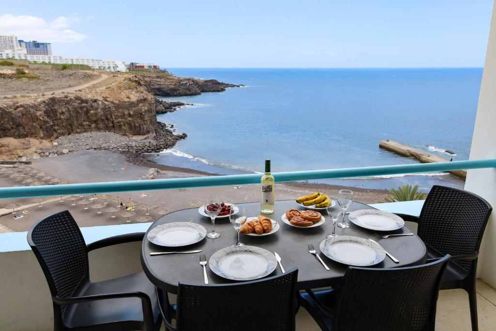 una mesa con comida y una botella de vino y el océano en Blue Horizon, en Callao Salvaje