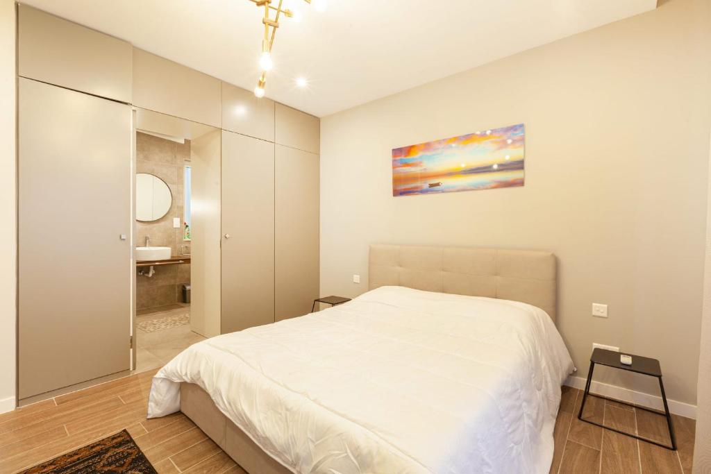 a bedroom with a white bed and a bathroom at Brand new 1BR in central MALTA-Hosted by Sweetstay in Tal-Pietà