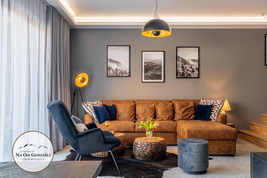 a living room with a brown couch and chairs at Apartamenty Na Osi Gondoli - wyciągi narciarskie, trasy rowerowe tylko 70 metrów in Szczyrk