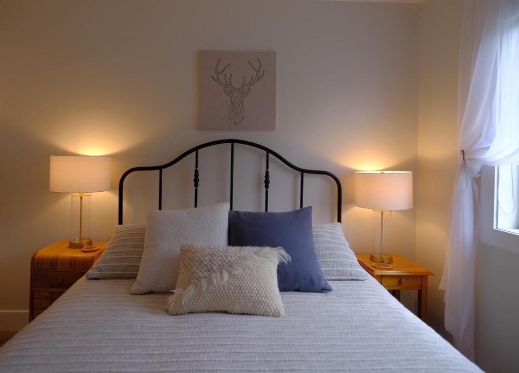 a bed with blue and white pillows and two lamps at Le Pimbina in Mont-Tremblant