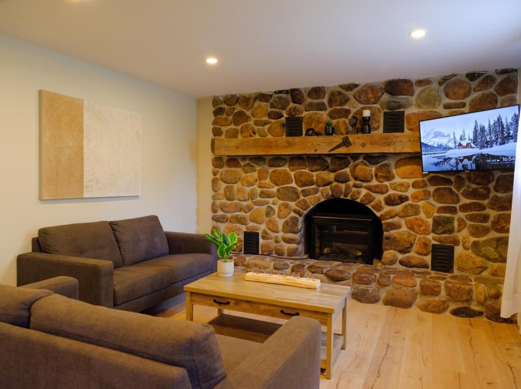 a living room with a stone fireplace with a tv at Le Pimbina in Mont-Tremblant