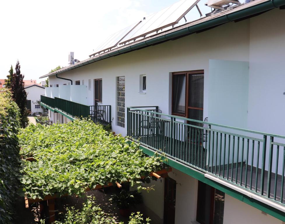 ein weißes Gebäude mit Balkonen und Bäumen an der Seite in der Unterkunft Pension Daniela Steiner in Podersdorf am See