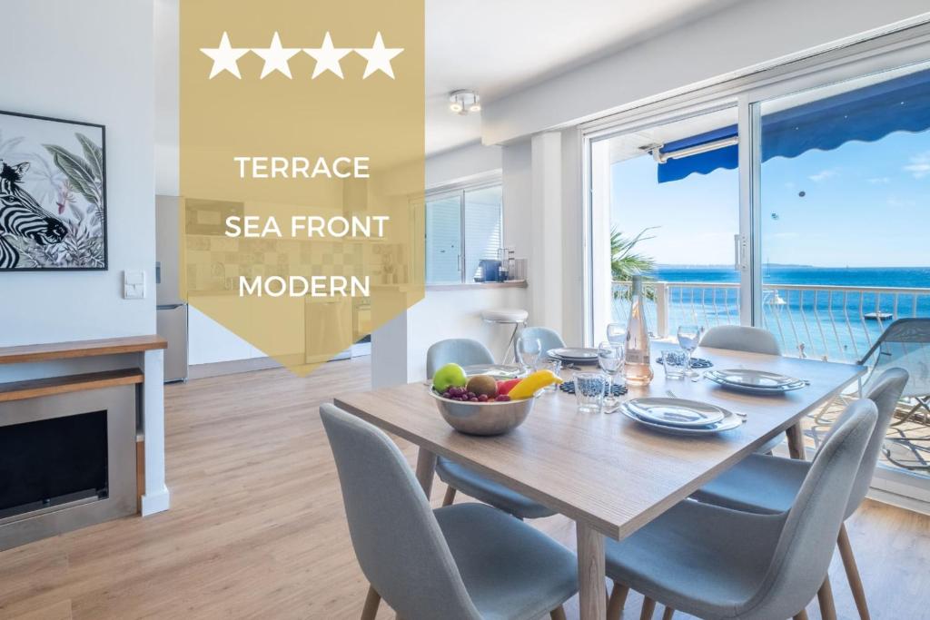 a dining room with a table and chairs with a ocean view at SERRENDY Renovated apartment with sea view in Cannes