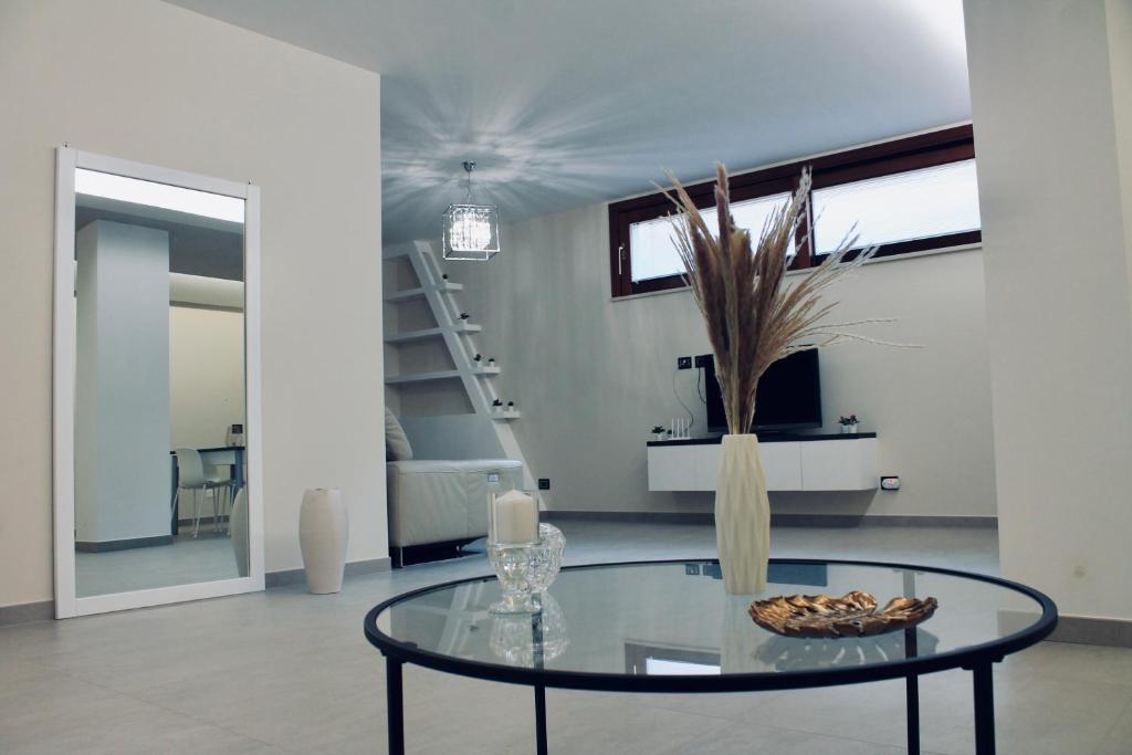 a living room with a glass table and a staircase at Di Rosa Apartment in Avola