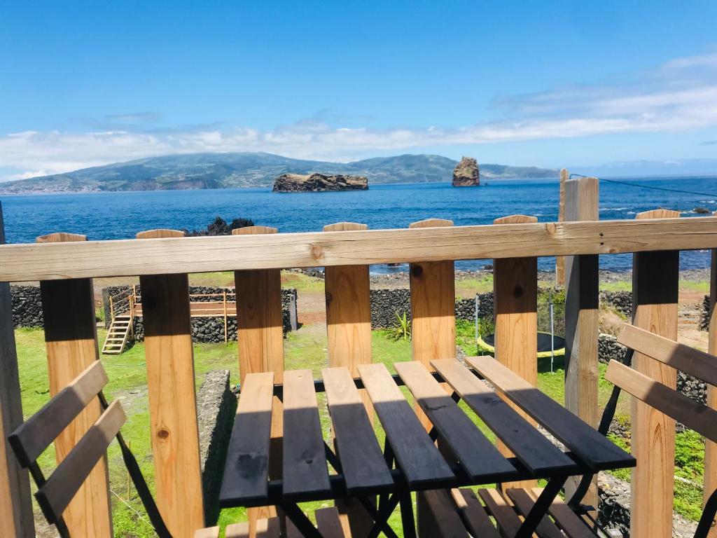 un banco de madera sentado en una valla con el océano en Casa-do-Mar en Madalena