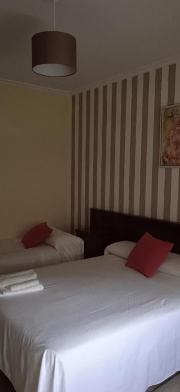 1 Schlafzimmer mit 2 Betten mit weißer Bettwäsche und roten Kissen in der Unterkunft O castiñeiro in Cerdedo