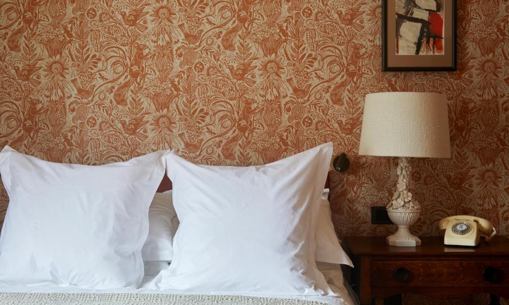 a bedroom with a bed with white pillows and a wall at The George In Rye in Rye