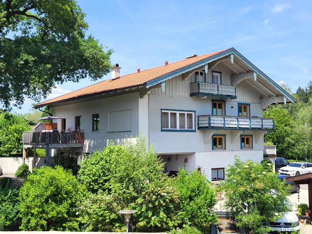 a white house with a balcony and trees at Haus Schönblick in Ruhpolding
