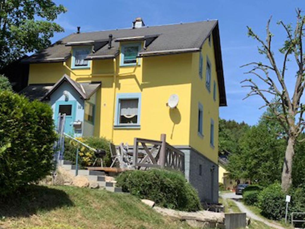 ein gelbes Haus mit schwarzem Dach in der Unterkunft Ferienhaus im Kumbachtal in Gräfenthal