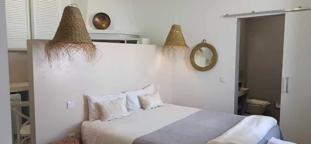 a bedroom with a white bed with two baskets on the wall at Casa Amarela Alojamento Local in Mértola
