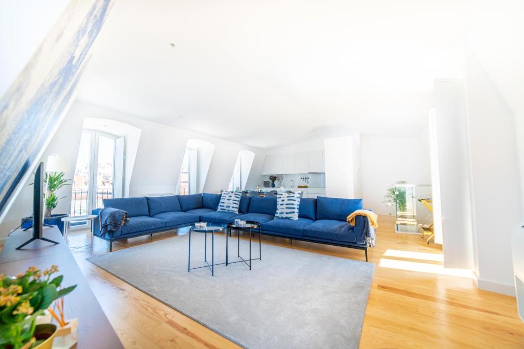 uma sala de estar com um sofá azul e um tapete em Blue by the River 4 - Unique Penthouse Duplex with a View em Lisboa