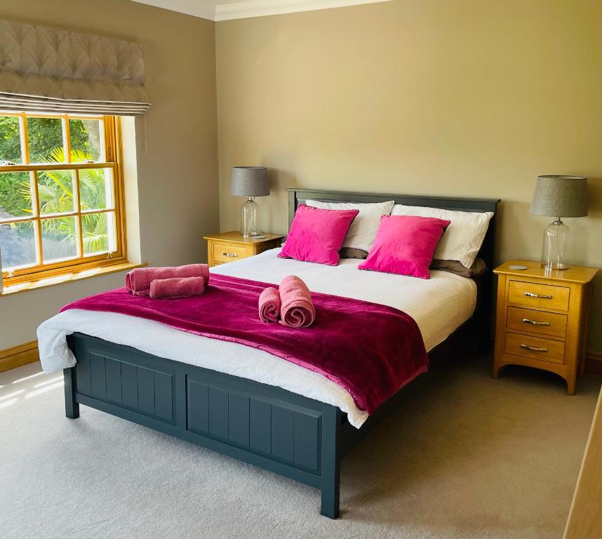 a bedroom with a large bed with pink pillows at Riverside House in York