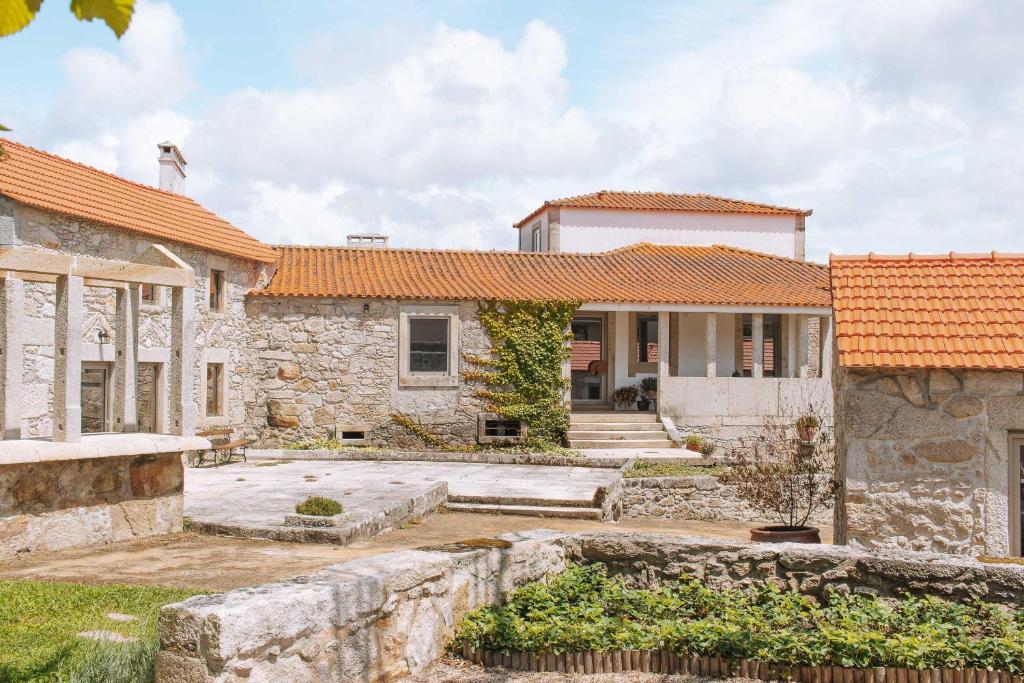 una antigua casa de piedra con techos naranjas en Quintal Country Houses en Vila Praia de Âncora