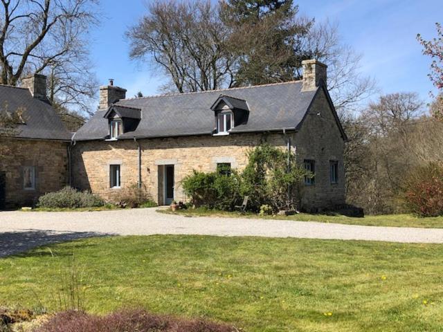 uma grande casa de tijolos com uma entrada em frente em merveilleux cottage dans parc de 7,5 hectares em Saint-Nicolas-du-Pélem