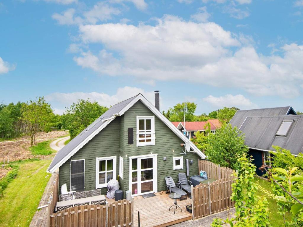 een klein groen huis met een houten terras bij 5 person holiday home in Hemmet in Hemmet