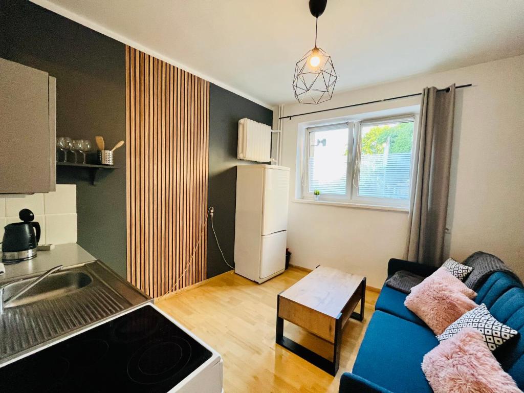 salon z niebieską kanapą i kuchnią w obiekcie Apartament Metro Center - Gdynia Centrum w mieście Gdynia