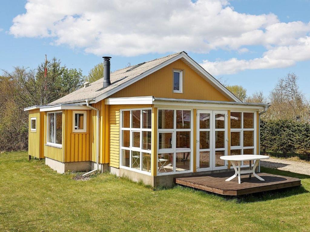 uma casa amarela com uma mesa em frente em Holiday home Thyholm XVI em Thyholm