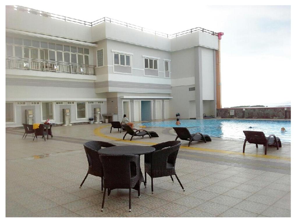 a large building with a pool and tables and chairs at Apartemen MTC in Manado