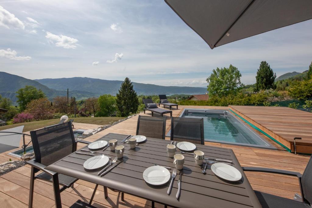 a table and chairs on a patio with a swimming pool at Appartement UBAC in Rovagny