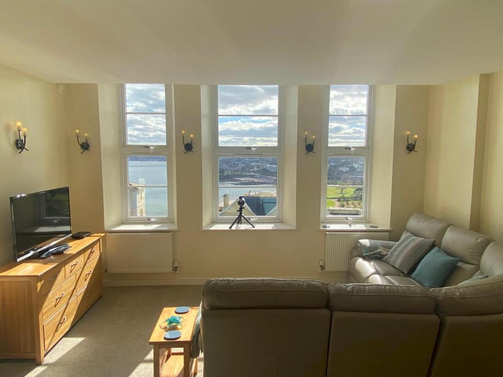 a living room with a couch and some windows at Pass the Keys Classy 2 bedroom apartment amazing beach views in Torquay