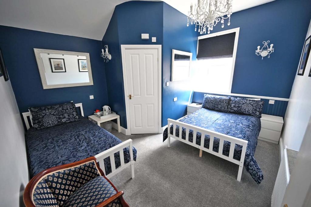 a blue bedroom with two beds and a chandelier at The Hathaways in Stratford-upon-Avon