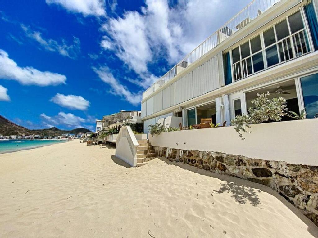 une maison sur une plage de sable avec l'océan dans l'établissement Paradis Caraibes 1, feet in the water in Grand Case, à Grand-Case