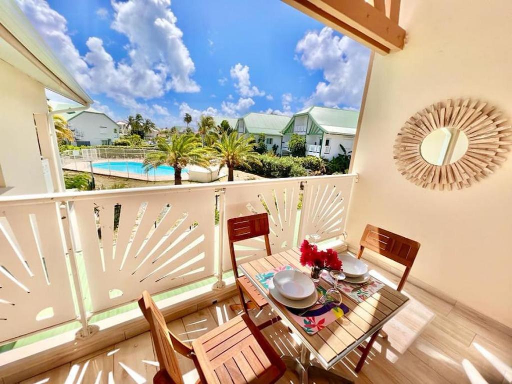 a balcony with a table and chairs and a pool at Maracuja 17, Orient Bay village, walkable beach at 100m in Orient Bay