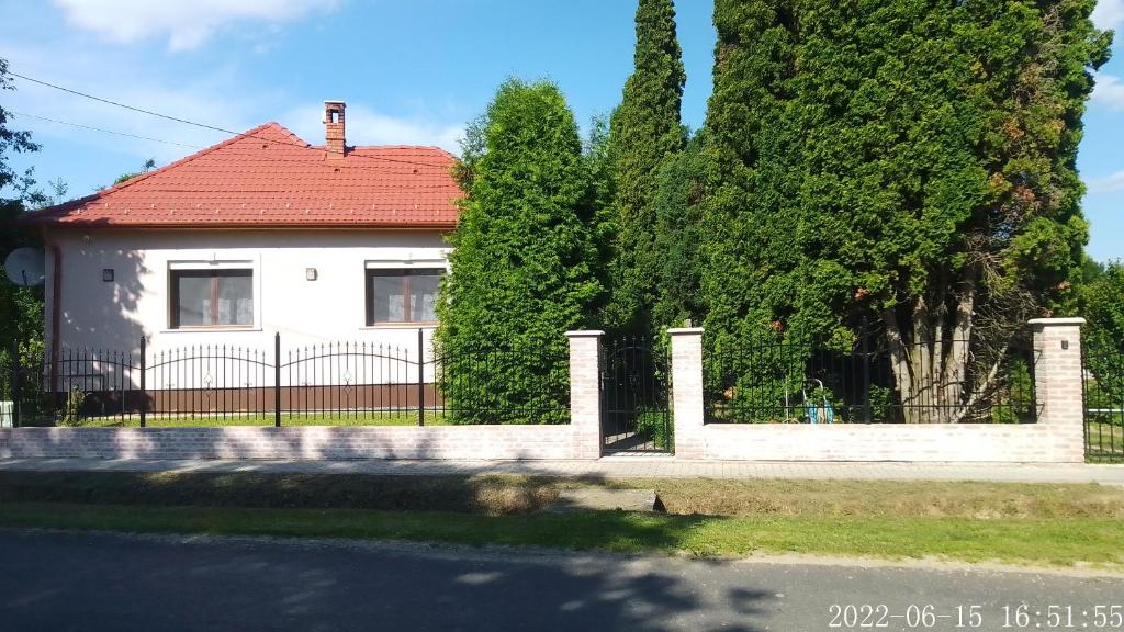 een wit huis met een hek en bomen bij Almafás Vendégház Őrség in Kerkakutas