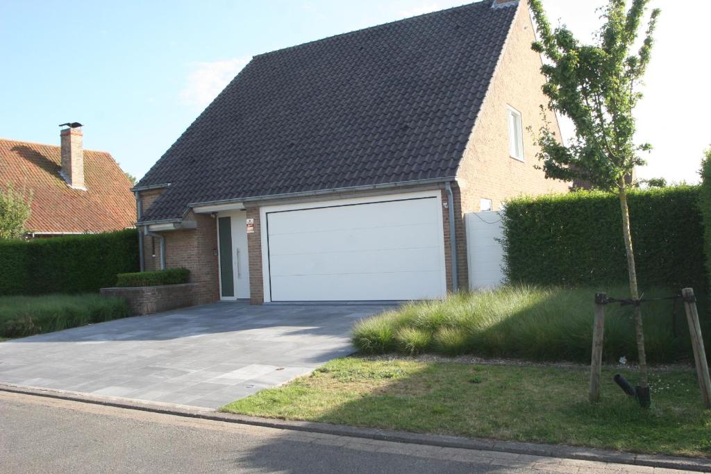 eine große weiße Garagentür an einem Haus in der Unterkunft Ashley’s Villa in Blankenberge