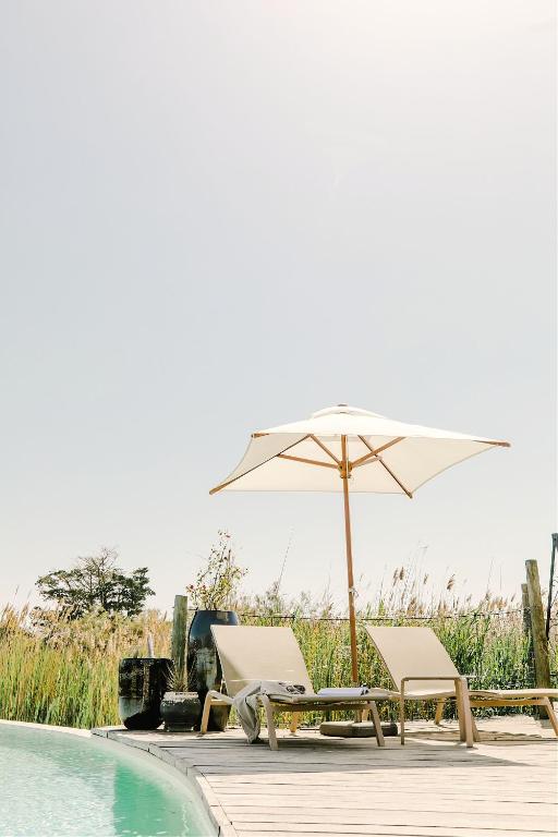 an umbrella and chairs next to a swimming pool at Hôtel Restaurant Les Arnelles in Saintes-Maries-de-la-Mer