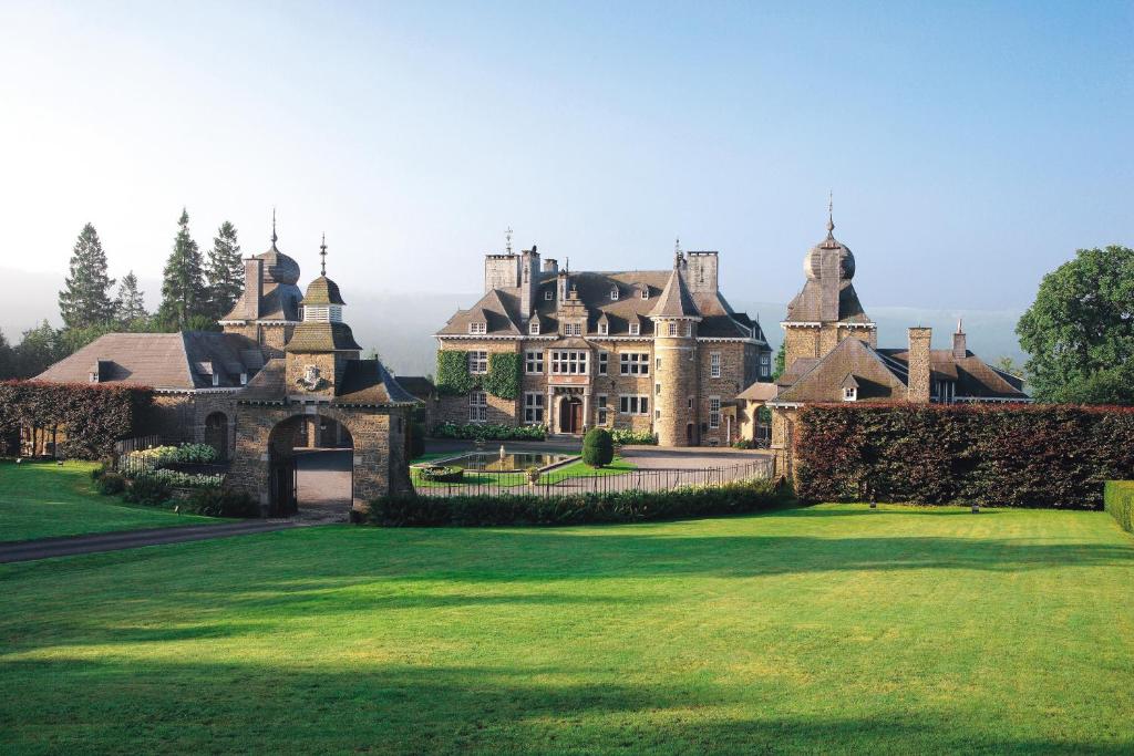 una casa grande con un césped verde delante de ella en Manoir de Lébioles en Spa