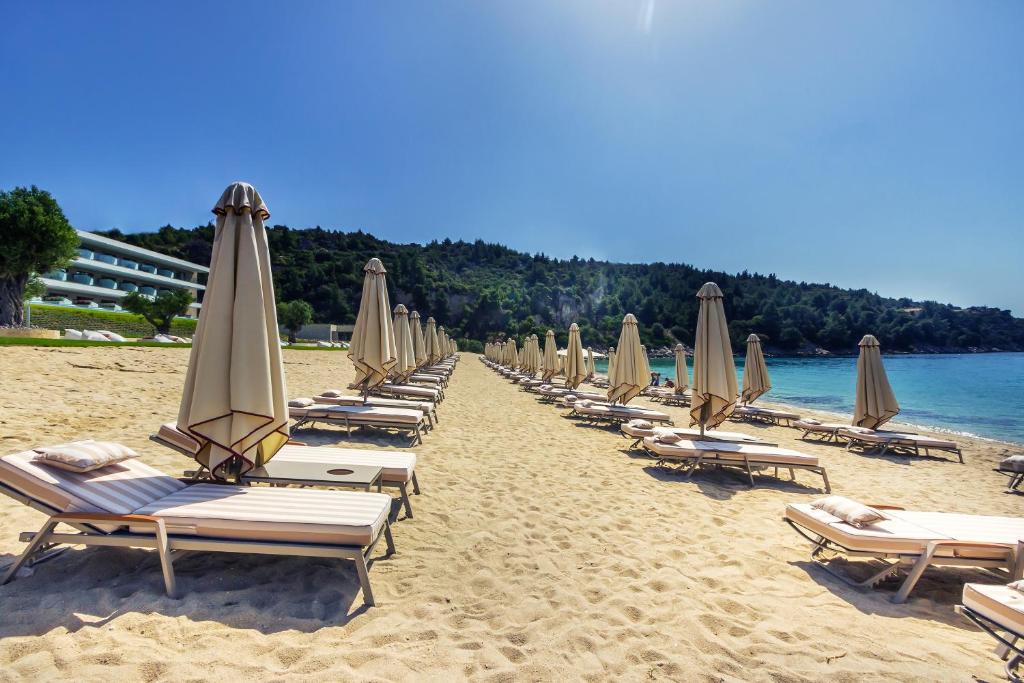 a line of chairs and umbrellas on a beach at Ammoa Luxury Hotel & Spa Resort in Nikiti