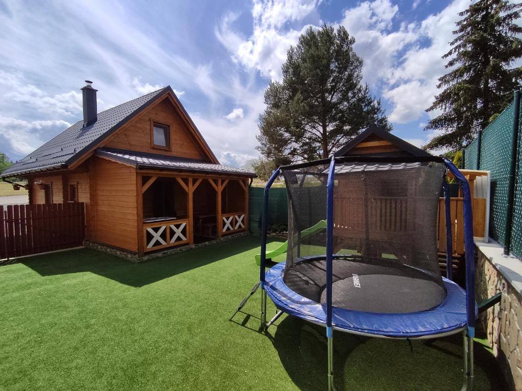 a small house with a trampoline in a yard at Drevenička Rybička in Liptovský Trnovec