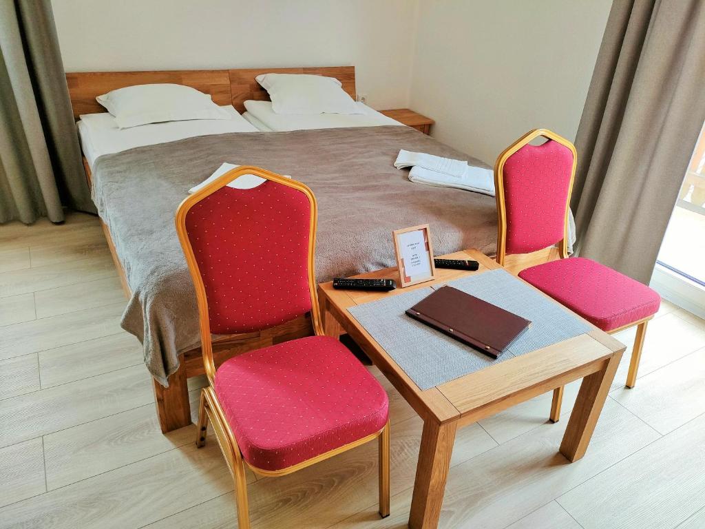 a bedroom with a bed and a table and chairs at AM BERG Hotel in Herzberg am Harz