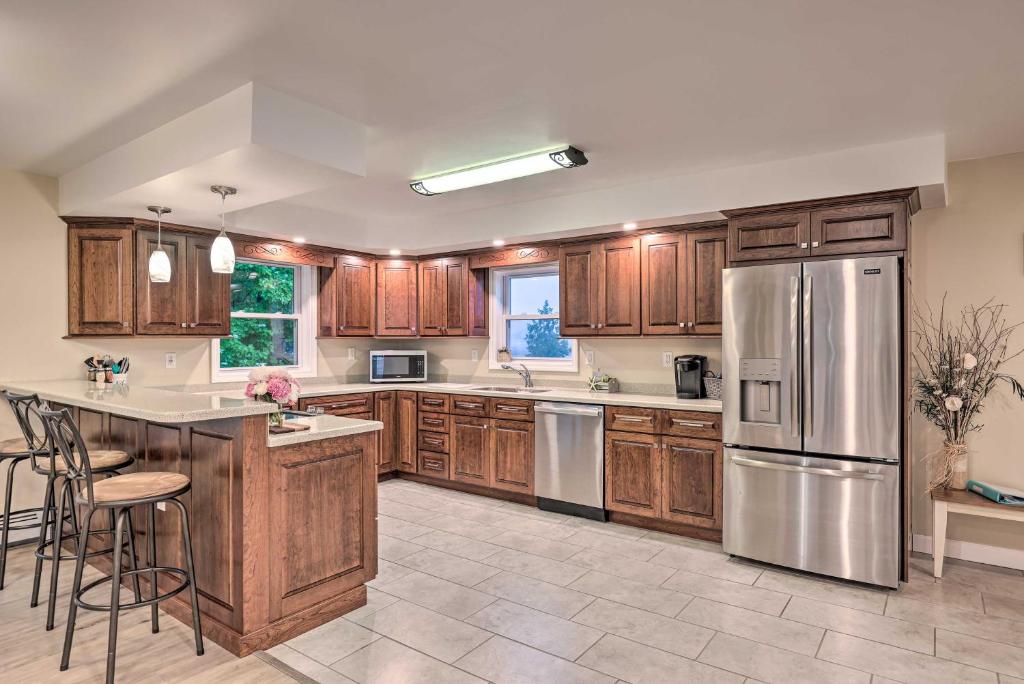a kitchen with wooden cabinets and a stainless steel refrigerator at Seneca Falls Retreat - Near Cayuga Wine Trail in Seneca Falls