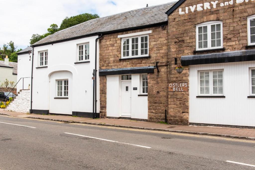 a brick building with white doors on a street at Earls Cottage in Usk