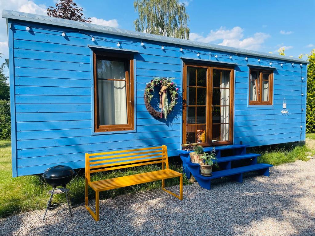 ein blaues winziges Haus mit einer Bank davor in der Unterkunft Glamour Maringotka v NP České Švýcarsko U Mluvících kamenů in Staré Křečany