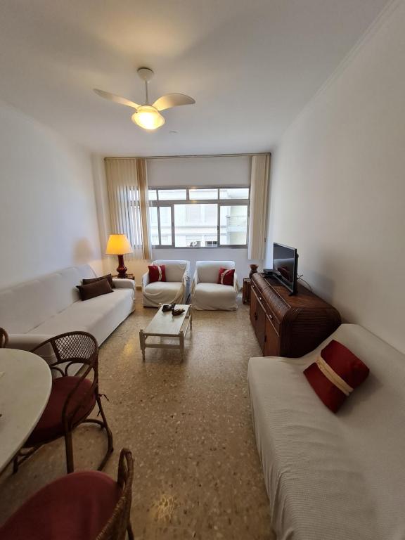 a living room with couches and a tv at Apartamento Das Conchas Praia das Pitangueiras in Guarujá