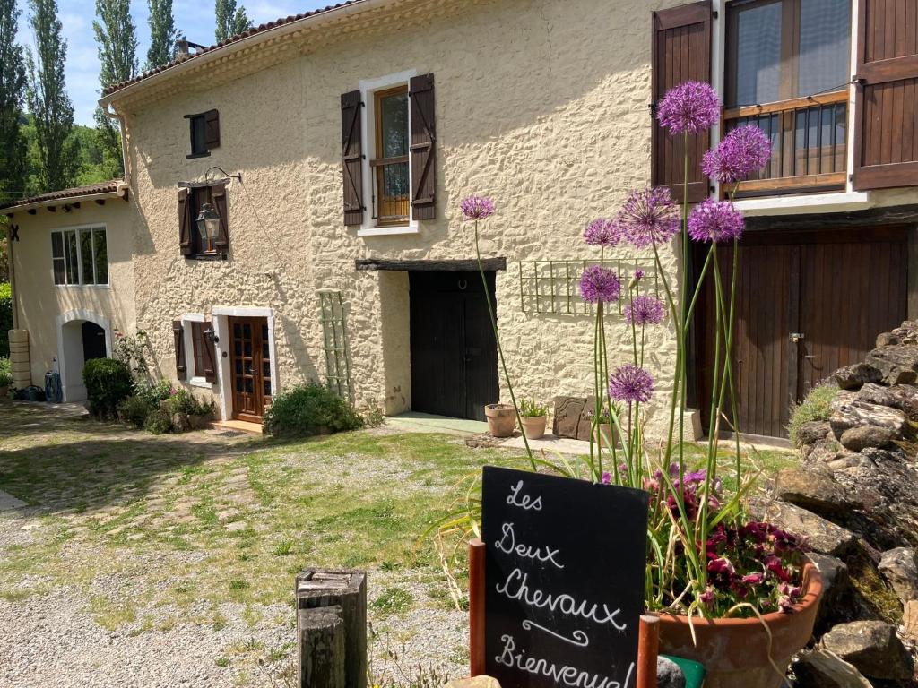 une maison avec un panneau devant elle et des fleurs violettes dans l'établissement Les Deux Chevaux Chambres d’Hôtes, à Rouvenac