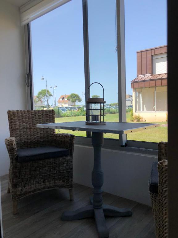 une table et deux chaises devant une fenêtre dans l'établissement Les valises sur le sable, 50m de la plage, parking, à Courseulles-sur-Mer