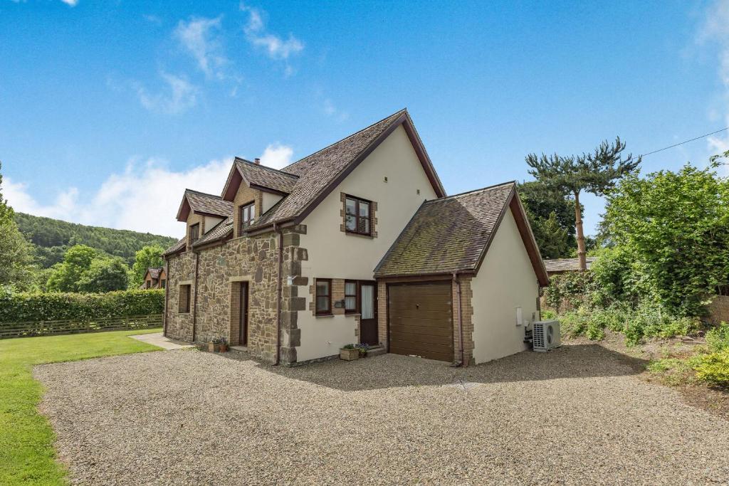 a large white house with a garage at Byne Brook Cottage in Wistanstow